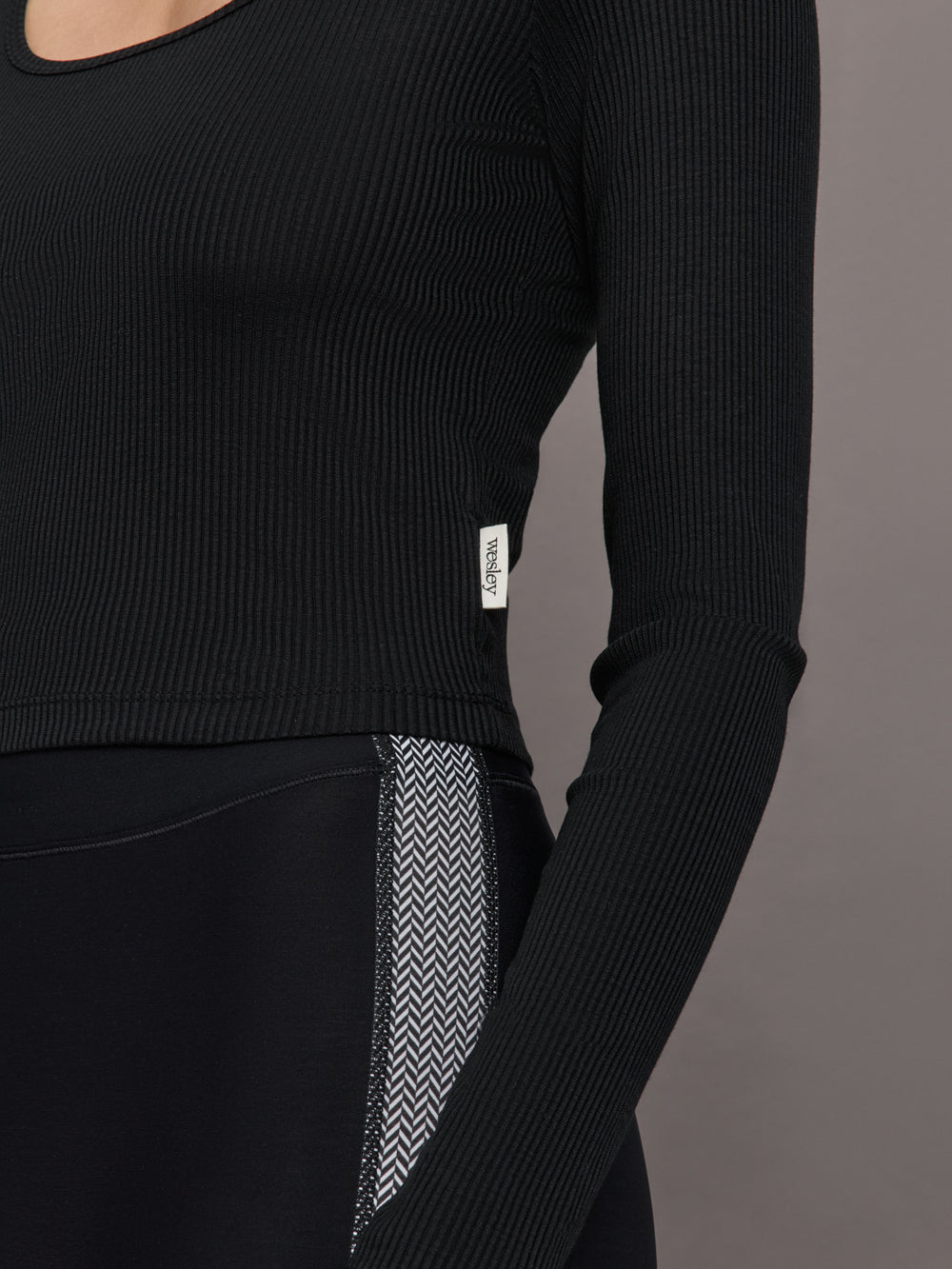 Model wears a long sleeved scoop neck black crop top. 