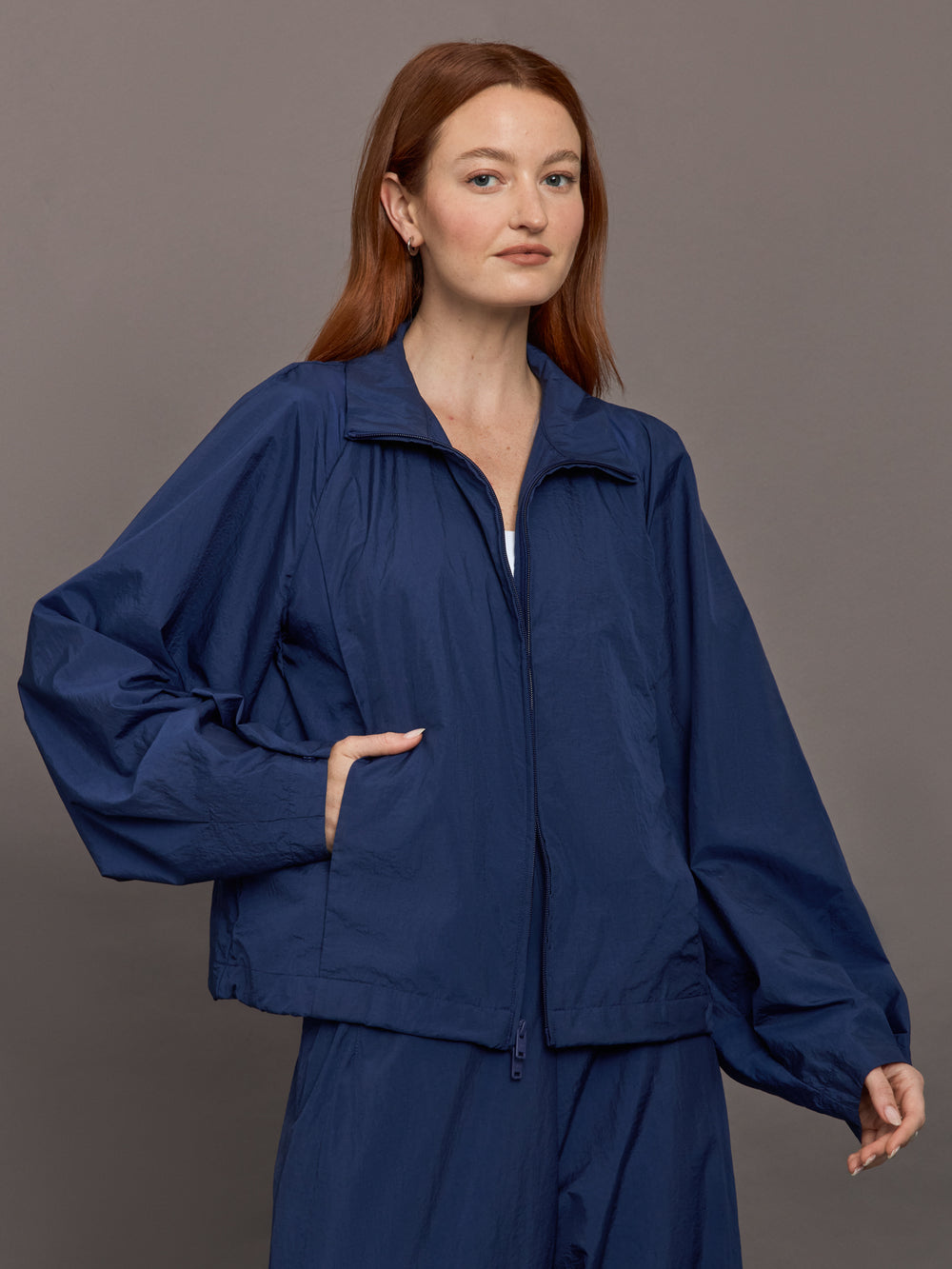 Model wears the Ulite nylon jacket in dark blue with a front zipper closure and relaxed fit.