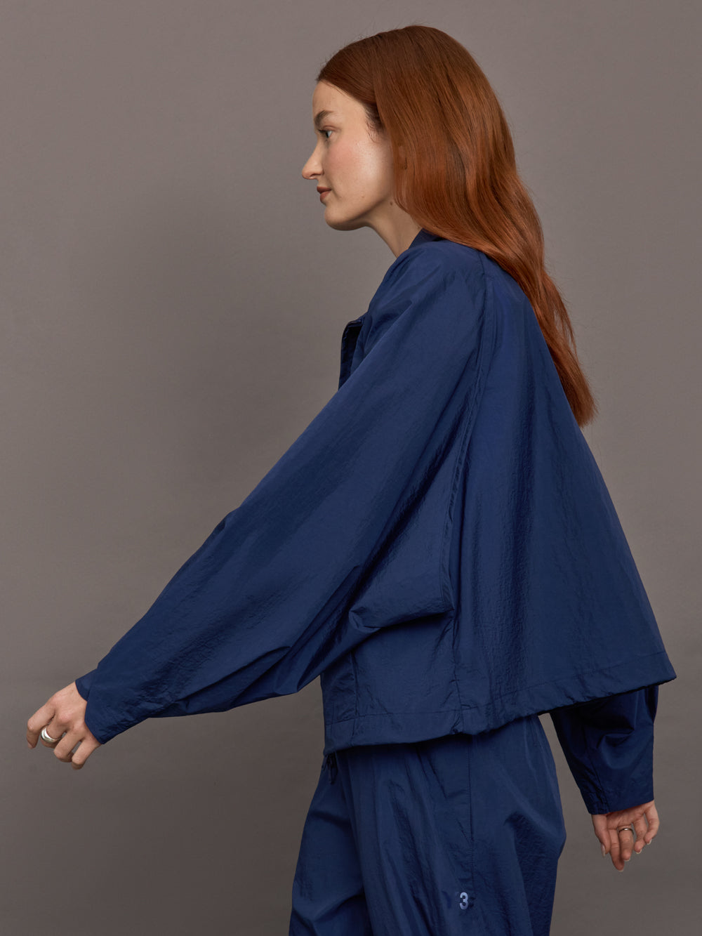 Model wears the Ulite nylon jacket in dark blue with a front zipper closure and relaxed fit.