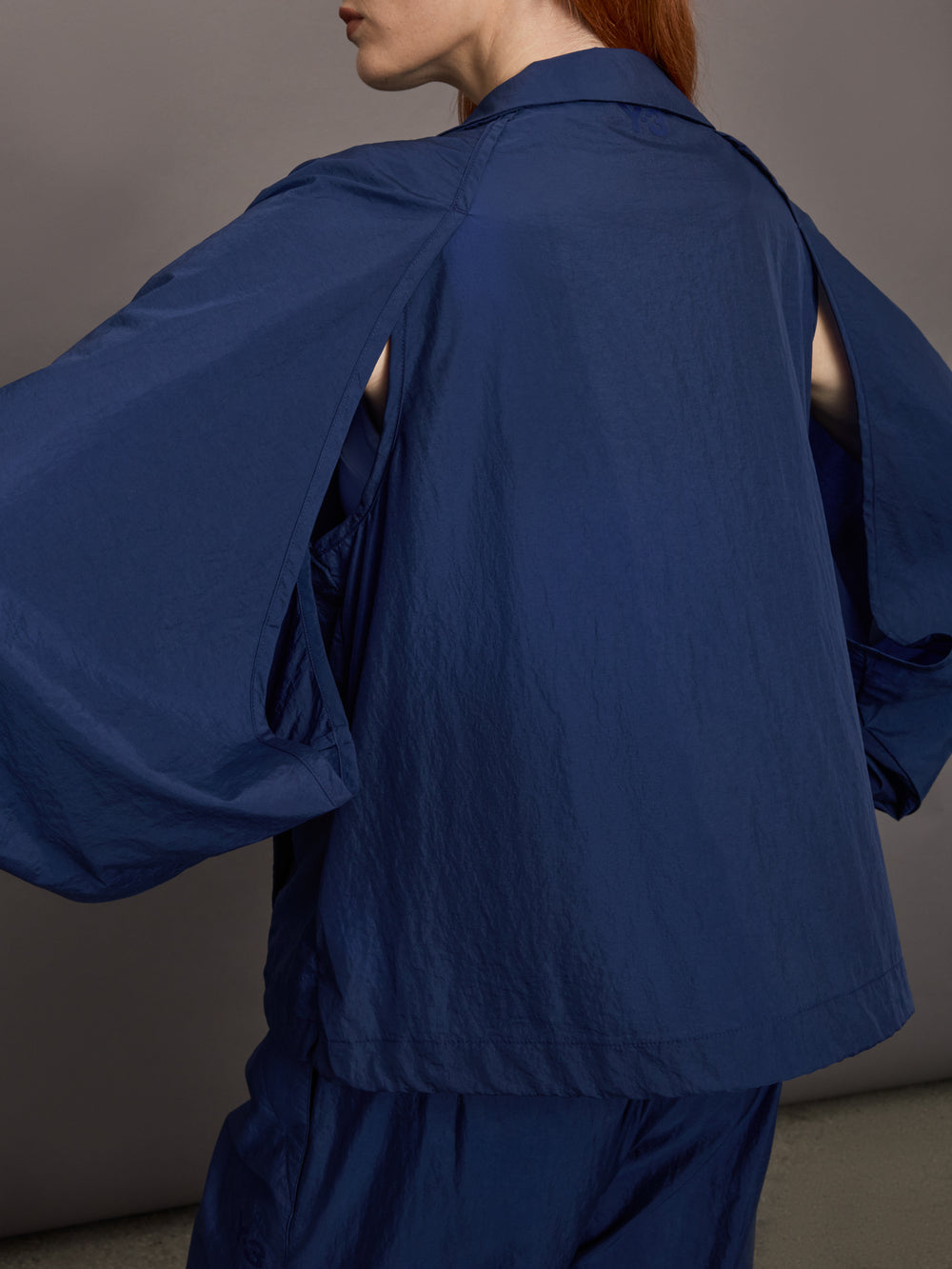 Model wears the Ulite nylon jacket in dark blue with a front zipper closure and relaxed fit.