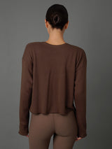 Model wears a french terry crew sweatshirt in Carafe color way against a grey background / back view. 