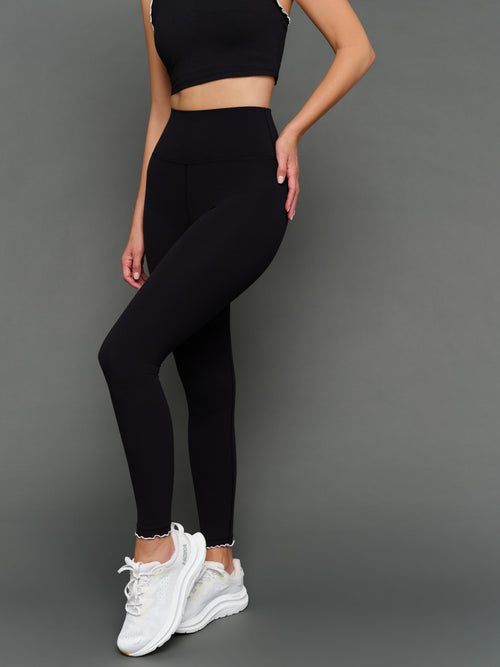Model is wearing Melt scallop edge legging in black white, front angled view.