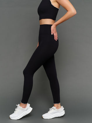 Model is wearing Melt scallop edge legging in black white, side view.