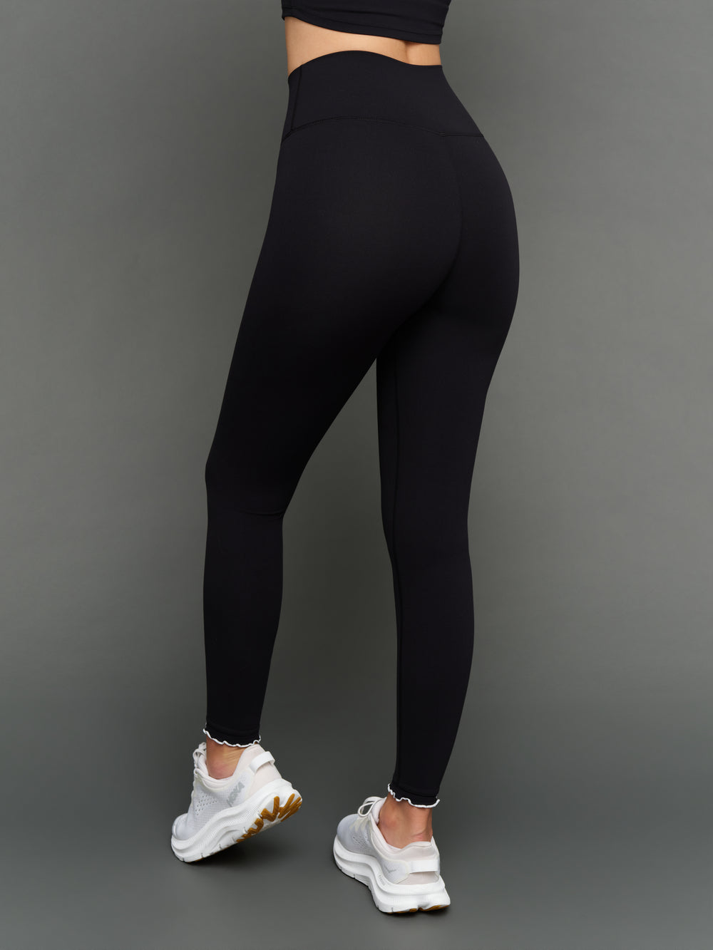 Model is wearing Melt scallop edge legging in black white, back full body view.