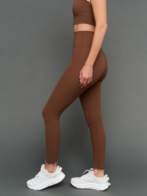 Model is wearing Melt scallop edge legging in carafe white, side profile view.
