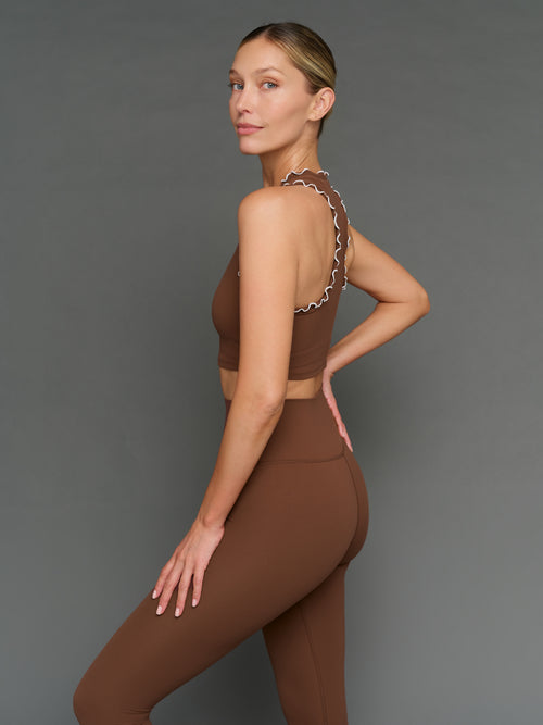 Model is wearing Melt scallop edge legging in carafe white, side profile view.