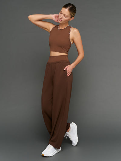 Model is wearing Melt scallop edge cropped bra in carafe white, styled with wide leg pants.