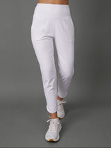 White high-waisted athletic leggings with a side pocket, shown on a model from the waist down against a solid gray studio background.
