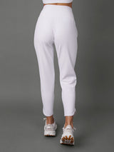 White activewear set featuring a one-shoulder crop top and high-waisted cropped leggings, shown from the back on a model against a solid gray studio background.