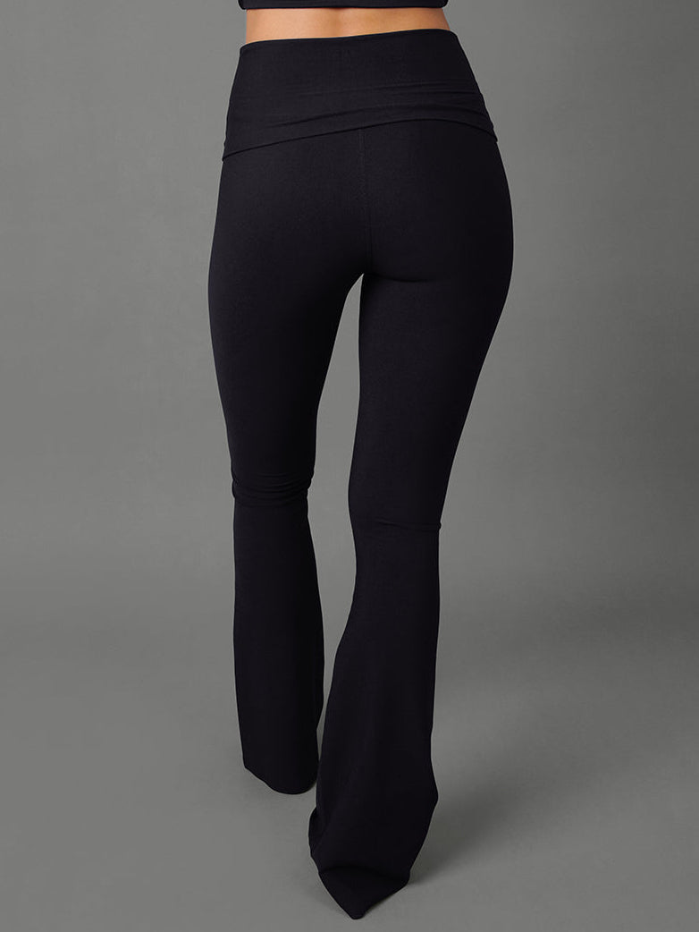 Model wears black bootcut leggings against a grey background, back view