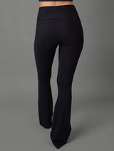 Model wears black bootcut leggings against a grey background, back view