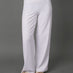 A model wearing a white two-piece activewear set consisting of a sports bra and high-waisted, wide-leg yoga pants, paired with beige slide sandals, set against a solid gray studio background.