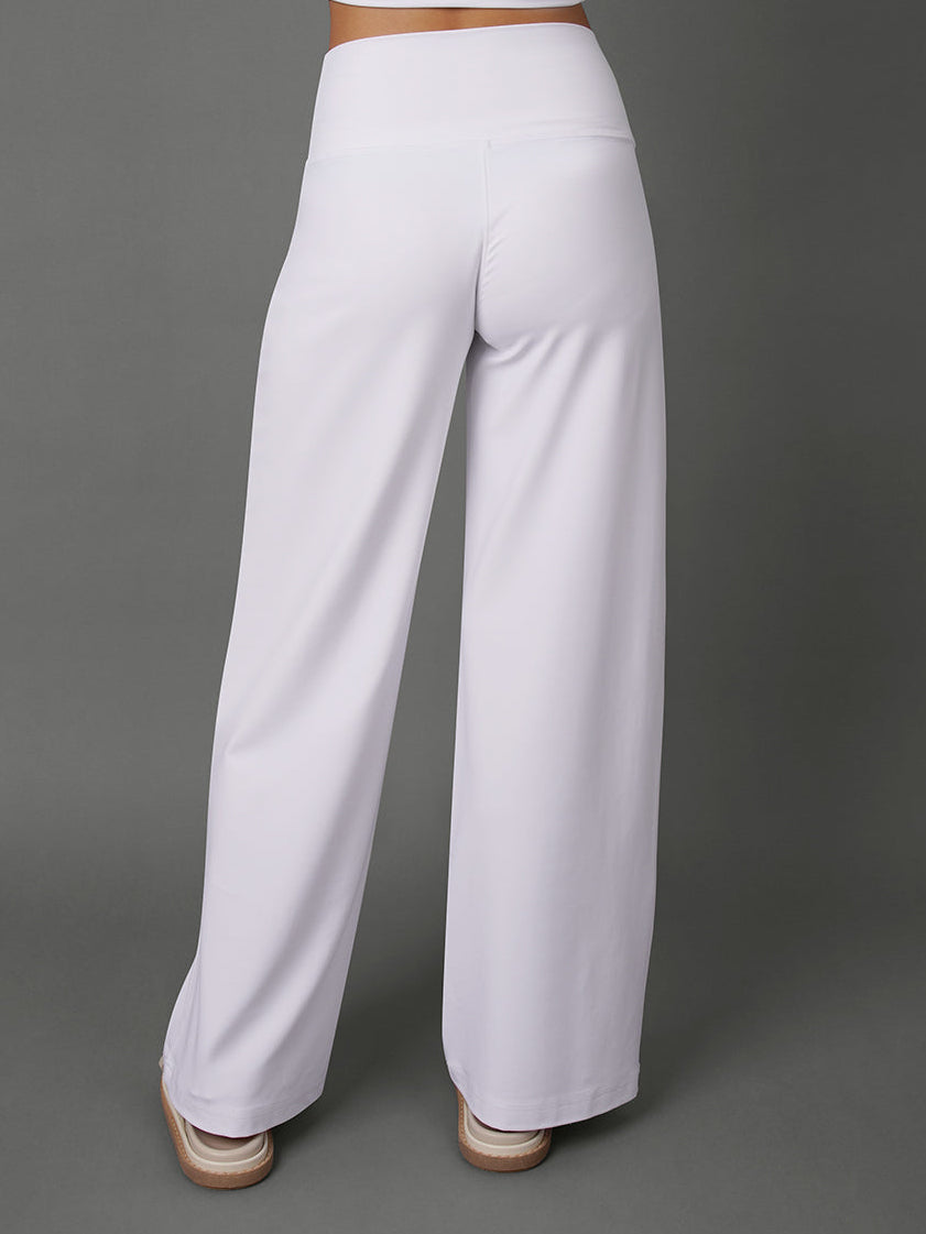 White wide-leg pants shown from the back on a model, paired with a matching white crop top, against a solid gray studio background.