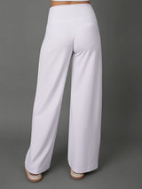 White wide-leg pants shown from the back on a model, paired with a matching white crop top, against a solid gray studio background.