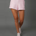 Model wears Pink Gingham french terry sweat shorts against a grey background, waist down shot. 