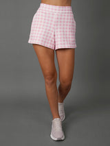 Model wears Pink Gingham french terry sweat shorts against a grey background, waist down shot. 