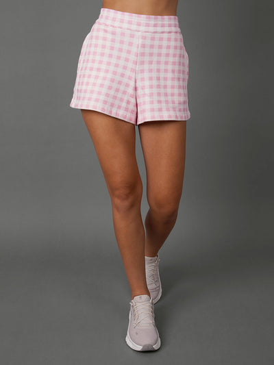 Model wears Pink Gingham french terry sweat shorts against a grey background, waist down shot. 