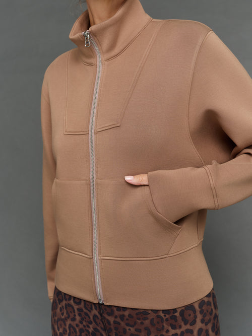 Model is wearing interlock full zip jacket caribou, zipper and pocket detail.