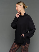 Model is wearing interlock mock neck pullover black, side profile view.