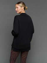 Model is wearing interlock mock neck pullover black, back view.