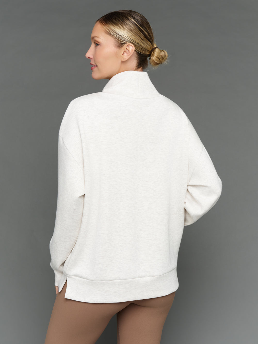 Model is wearing interlock mock neck pullover moonbeam heather, back view.