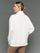 Model is wearing interlock mock neck pullover moonbeam heather, back view.