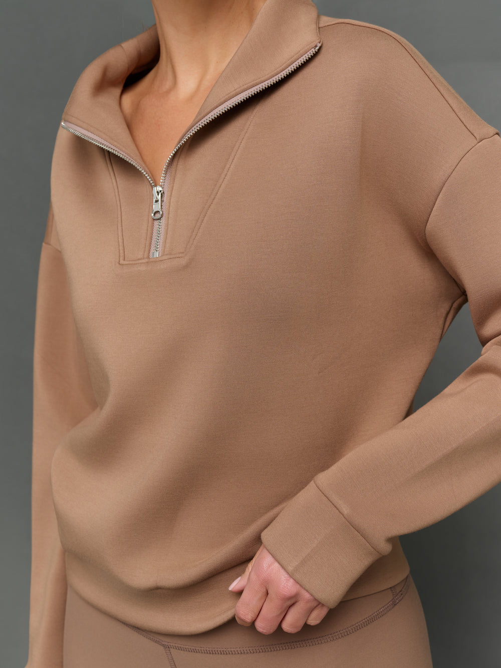 Model is wearing interlock half zip pullover caribou, zipper close-up detail.