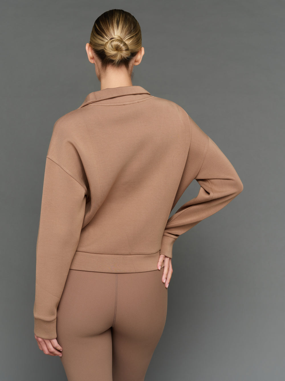 Model is wearing interlock half zip pullover caribou, back view.