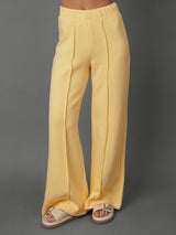 Model wears yellow interlock pants against a grey background.