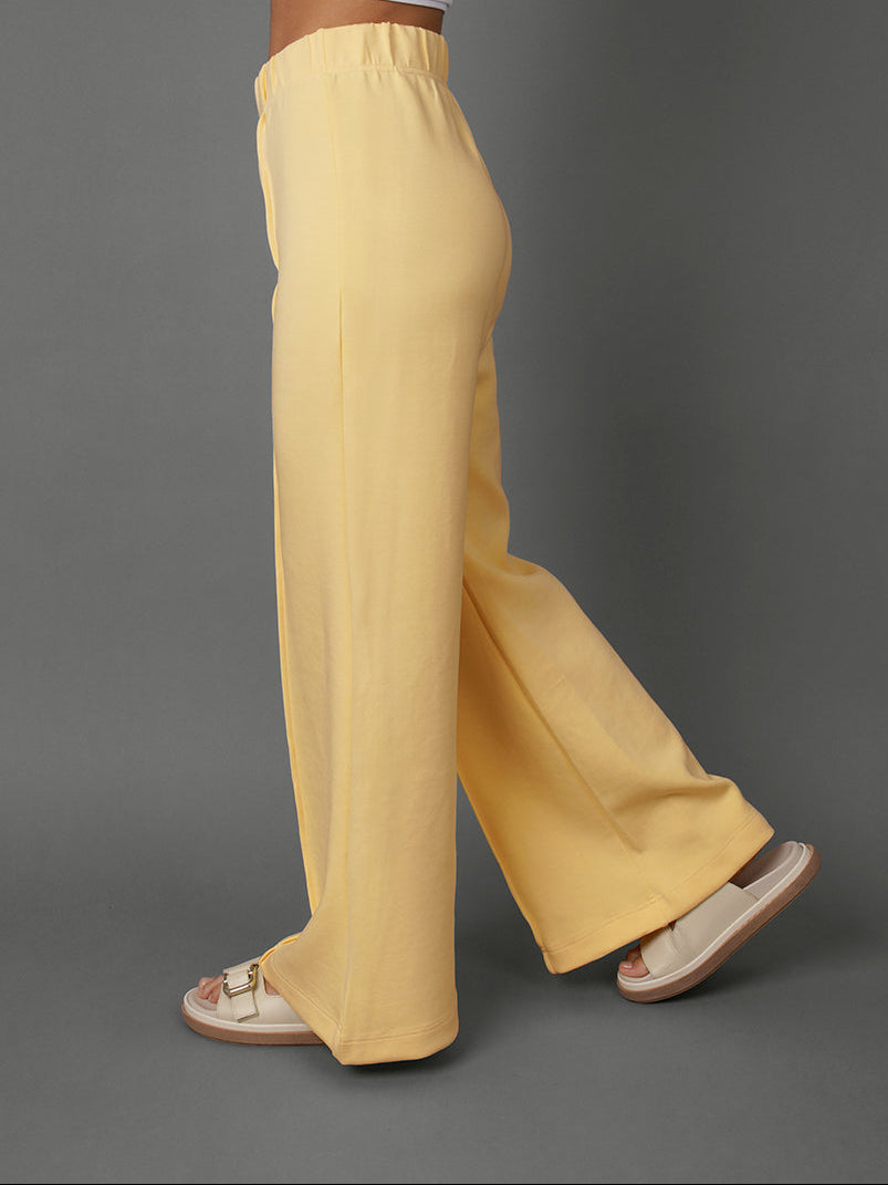 Model wears yellow interlock pants against a grey background.