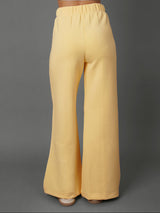 Model wears yellow interlock pants against a grey background.