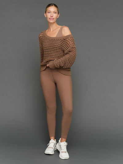 Model is wearing wide neck open knit sweater in caribou, front full body view.