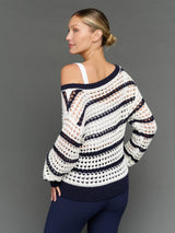 Model is wearing wide neck open knit sweater white navy, back three-quarter view.