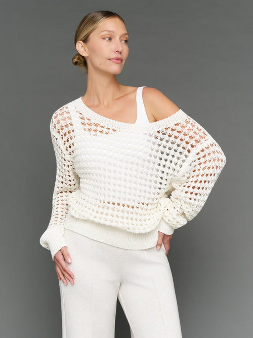 Model is wearing wide neck open knit sweater white, front three-quarter view.