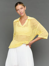 Model is wearing open knit polo sweater pale banana, front view.