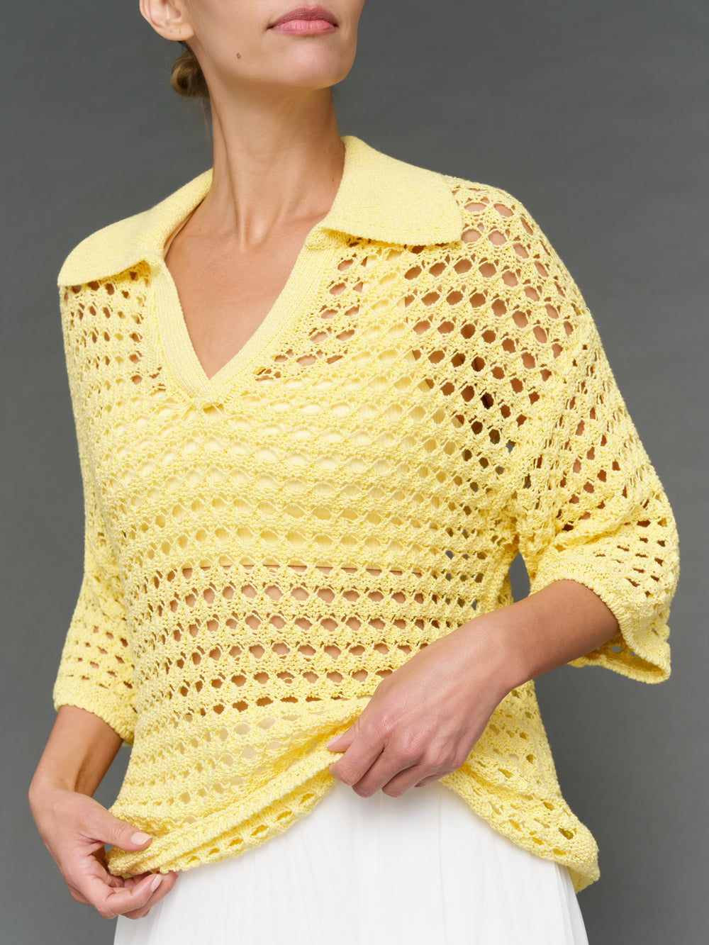 Model is wearing open knit polo sweater pale banana, front close-up detail.
