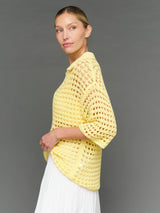 Model is wearing open knit polo sweater pale banana, side profile view.