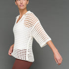 Model is wearing open knit polo sweater white, side view.