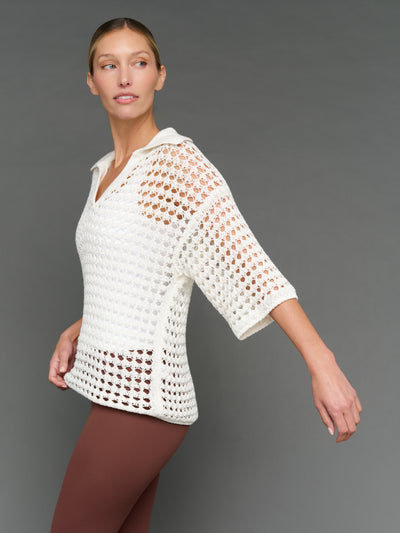 Model is wearing open knit polo sweater white, side view.