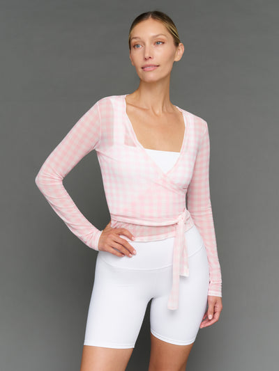 Model wearing a light pink long-sleeve top and white shorts against a gray background