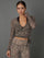 Model wears a zebra print mesh wrap top against a grey background