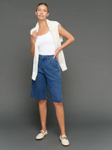 Model is wearing chambray bermuda short dark wash styled with knit layer, full body view.