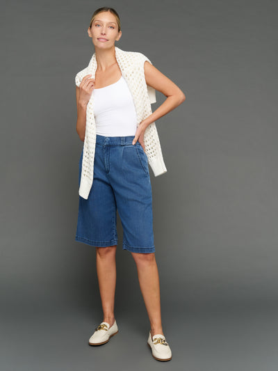 Model is wearing chambray bermuda short dark wash styled with knit layer, full body view.