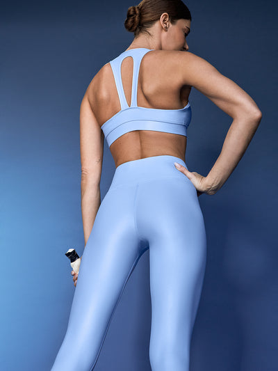 Model is wearing the Action Bra 2.0 and High Rise 7/8 Legging in Takara Shine in Serenity shown from the back with racerback cutout detail.