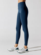 Side view of Diamond Compression high-rise full-length leggings in French Navy with white sneakers.