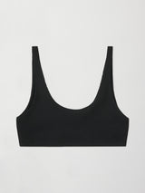 Flat lay of ribbed scoop neck sports bra in black on white background.